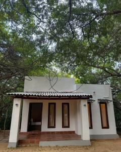 a small white house with trees in front of it at In the Wild by RoamCeylon in Polonnaruwa