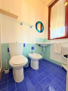 un bagno piastrellato blu con un water e un lavandino di Nido Colorato B&B a Fontane Bianche