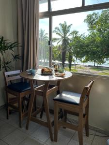 a table and chairs with food on it in front of a window at Apartamento com vista pro mar no Centro de Ubatuba - com estacionamento 2 quartos e cozinha completa in Ubatuba