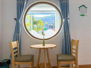 a table with two chairs and a round window at Homestay Phúc Lộc in Îlot du Sud