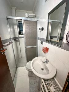 a bathroom with a sink and a toilet and a mirror at Apartamento com vista pro mar no Centro de Ubatuba - com estacionamento 2 quartos e cozinha completa in Ubatuba