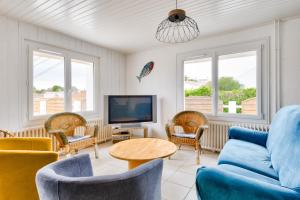 a living room with a blue couch and chairs and a tv at Maison à Barbâtre pour 10 - 450m de la plage in Barbâtre