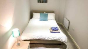 a small bedroom with a white bed and a lamp at StayZo Modern Studio Apartment 1 in Bradford City in Bradford