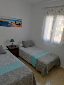 a bedroom with two beds and two windows at Mirador del Golf con piscina in Islantilla