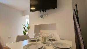 a white table with plates and wine glasses on it at De Parys Self-Catering Flat 2 in Bedford in Bedford
