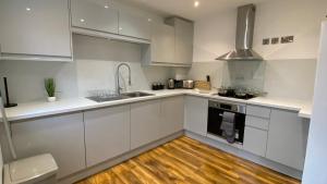 a kitchen with white cabinets and a wooden floor at De Parys Self-Catering Flat 2 in Bedford in Bedford