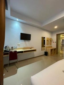 a bedroom with a desk and a television on the wall at Villa SIDAPORE JD in Lamobuang