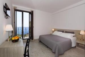 a bedroom with a bed and a table and a window at Villa Astoria in Taormina