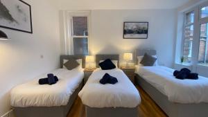 three beds in a room with black pillows on them at De Parys Flat 1 in Bedford in Bedford