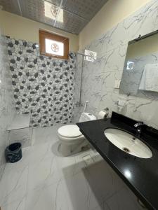 Un baño con un inodoro blanco y un lavabo. en Relax Inn Skardu, en Skardu