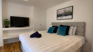 a bedroom with a large white bed with blue pillows at StayZo - Executive City Centre Apartment 2 in Bradford