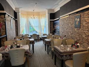 a restaurant with tables and chairs and a stone wall at Athol House in Douglas