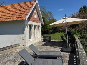 Un patio con una mesa y sillas y una sombrilla. en Chalet TOUSVENTS, en Saint-Georges-de-Didonne