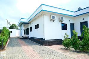 a white building with a blue roof and a brick driveway at Chic villa with pool in Kribi
