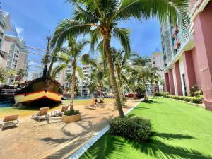 a boat is parked next to a lawn with palm trees at Accommodation with waterpark in Pattaya South