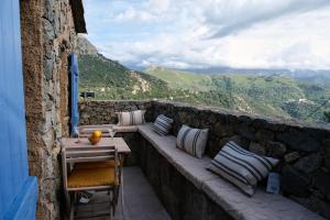 a balcony with a table and pillows on a stone wall at CASA MIA - Maison et chambres à louer à Corbara in Corbara