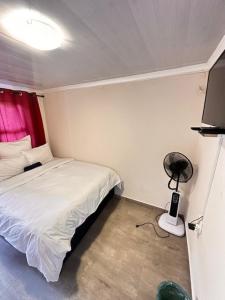 a small bedroom with a bed and a fan at K-Lodge in Pietermaritzburg