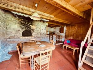 a dining room with a table and a stone fireplace at Gîte rural La Grange en pleine nature à La Pesse in La Pesse