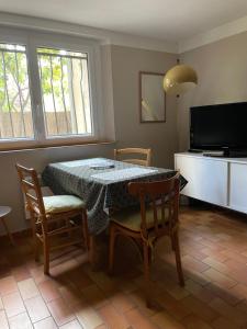 a dining room with a table and chairs and a television at 2 appartements calmes in Fréjus