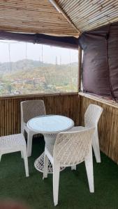 una mesa y sillas en un porche con vistas en Bambooz Bell cottage and camps I Kasauli I Lake View & Trekking, en Kasauli 33 fotos más