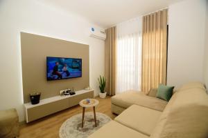 a living room with a couch and a tv on a wall at Seaside Serenity Apartments - Tirana Resort Radhime in Vlorë