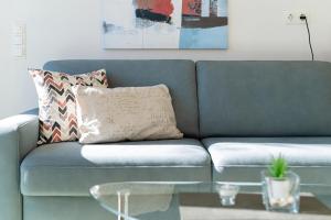 a blue couch in a living room with a glass table at K2 Bungalow - Strandhaus Königsberger Allee 8 - FERIENDOMIZIL HOLLICH in Grömitz