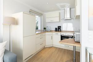 a kitchen with white cabinets and a wooden table at K2 Bungalow - Strandhaus Königsberger Allee 8 - FERIENDOMIZIL HOLLICH in Grömitz