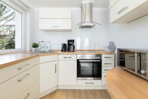 a kitchen with white cabinets and a window at K2 Bungalow - Strandhaus Königsberger Allee 8 - FERIENDOMIZIL HOLLICH in Grömitz +25 photos