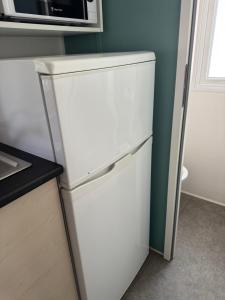 Un refrigerador blanco en una cocina con microondas. en Mobil home propre et récent, en Argelès-sur-Mer