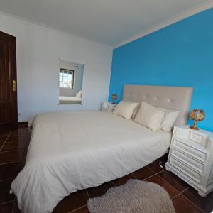 Un dormitorio con una gran cama blanca con una pared azul. en Rocky3, en Angra do Heroísmo