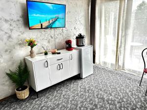 a living room with a white cabinet and a television on a wall at Muller Residence in Timişoara