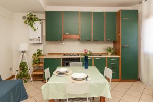 a kitchen with green cabinets and a table with chairs at Ca di Mar 4 in Caorle