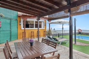 una mesa de madera con sillas y una sombrilla en el patio en Vv Terrazita, en Tijarafe