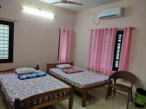 two beds in a room with pink curtains at VILLA VISTA Apt RENTAL in Alleppey