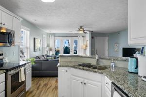 a kitchen with white cabinets and a living room at Sea Drift 102 by Carolina Beach Realty in Carolina Beach