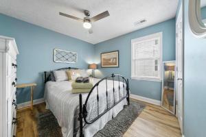 a bedroom with blue walls and a bed with a fan at Sea Drift 102 by Carolina Beach Realty in Carolina Beach