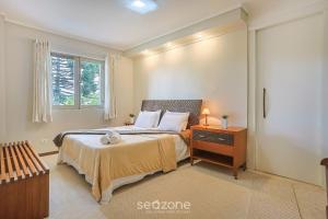 a bedroom with a bed with a nightstand and a window at Apto c/ Linda Vista em Campos do Jordão LVR0003 in Campos do Jordão