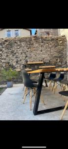 un tavolo in legno con 2 sedie e un muro di pietra di Chez Louis a Saint-Flour