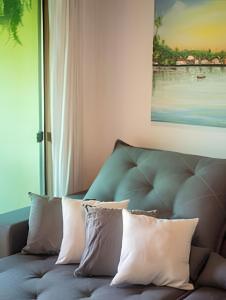 a couch with pillows sitting next to a window at 450m PRAIA de Taperapuan; Piscina; 2 quartos; WiFi 300 mbs; Churrasqueira; Estacionamento Gratuito 1 carro in Porto Seguro