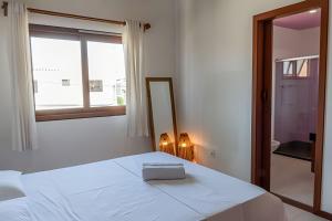 a bedroom with a white bed with a mirror and a window at 450m PRAIA de Taperapuan; Piscina; 2 quartos; WiFi 300 mbs; Churrasqueira; Estacionamento Gratuito 1 carro in Porto Seguro +48 photos