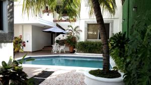 a swimming pool with a palm tree next to a building at Hotel El Almendro in Managua