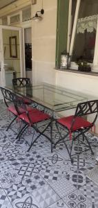a glass table and two red chairs on a tile floor at Chez sylvie in Soyaux
