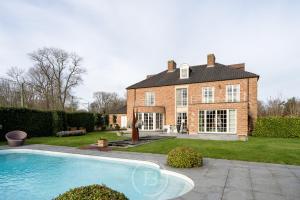 a large brick house with a swimming pool in front of it at Blauw aan zee in De Panne