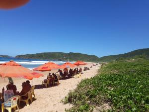 a group of people sitting under umbrellas on a beach at Chalé em Búzios 100m da Praia de Tucuns in Búzios