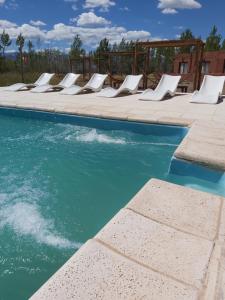 a pool with white lounge chairs next to the water at Hotel boutique pukarainca in Uspallata