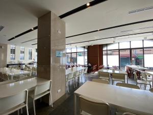 a restaurant with white tables and chairs and windows at Hotel Jiji Plus in Ch'ai-ch'iao-t'ou