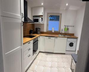 a kitchen with white cabinets and a washer and dryer at Sonnenhang Bayern in Grabenstätt