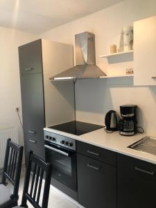 eine Küche mit Herd und Kühlschrank und zwei Stühlen in der Unterkunft Ferienwohnung Winterberg in Winterberg + 11 Fotos