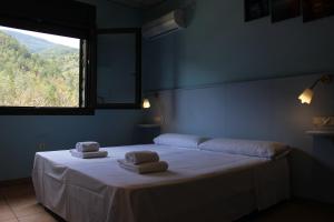 a bedroom with a bed with two towels on it at Hotel Al Riu in Bagá