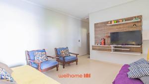 a living room with two chairs and a flat screen tv at Casa Aconchegante em Bertioga a 700m da Praia in Bertioga